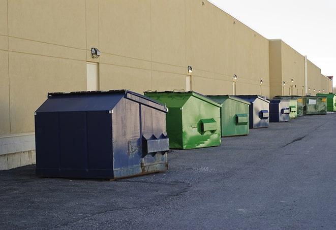 a fleet of red and blue construction dumpsters available for use in Anniston AL